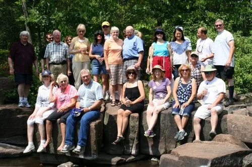 A large group of CWN members gathered on rocks in a sunny park